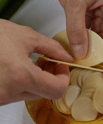 Ein Priester bricht das Brot während eines Gottesdienstes am 10. Juli 2014 in Offenbach.