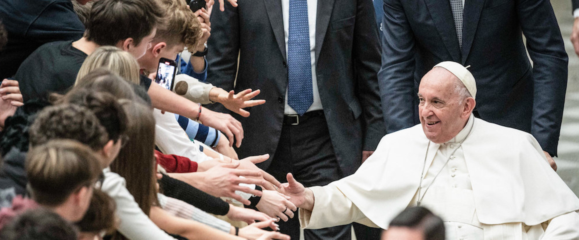 Jugendliche reichen Papst Franziskus ihre Hände bei dem vom italienischen Netzwerk 'Schulen des Friedens' geförderten Treffen in der Audienzhalle, am 28. November 2022 im Vatikan.