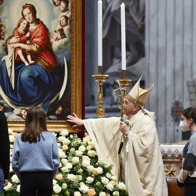 Papst Franziskus berührt das Gemälde einer Madonna, während des Gottesdienstes am Hochfest Christkönig, am 21. November 2021 im Vatikan. Jugendliche stehen um ihn herum.