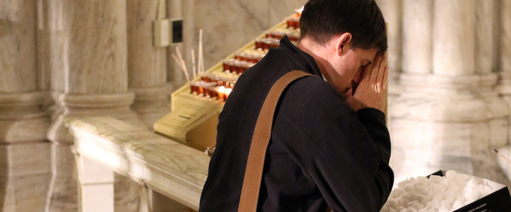 Ein junger Mann betet in einer Kniebank während einer Vigil in der Saint Patrick's Cathedral in New York am 7. Dezember 2016. Er kniet und hat die Hände zum Gebet gefaltet.