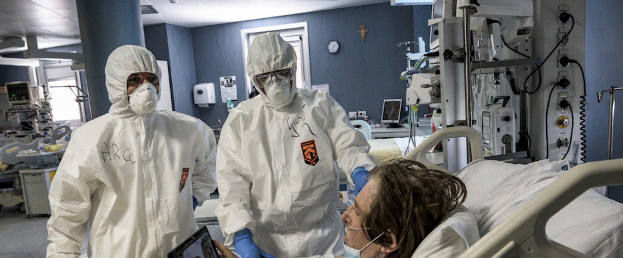 Ärzte und Pfleger in Schutzkleidung stehen am 29. April 2020 neben einem im Bett liegenden Covid-19-Patienten auf der Intensivstation des Krankenhauses San Filippo Neri in Rom. Der Mann hält ein Tablet zum Skypen.